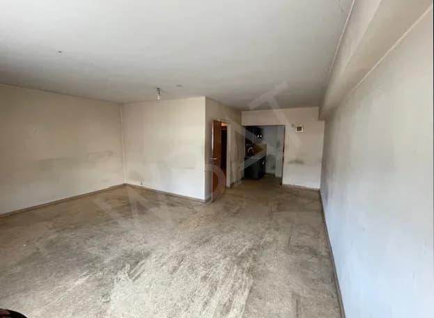 Séjour vide avant rénovation, sol et murs abîmés