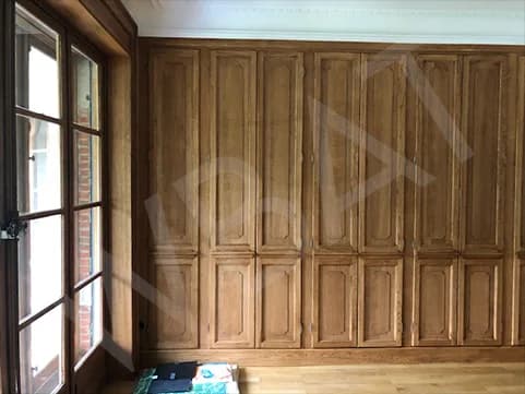 Dressing terminé en bois avec portes moulurées sur tout le mur