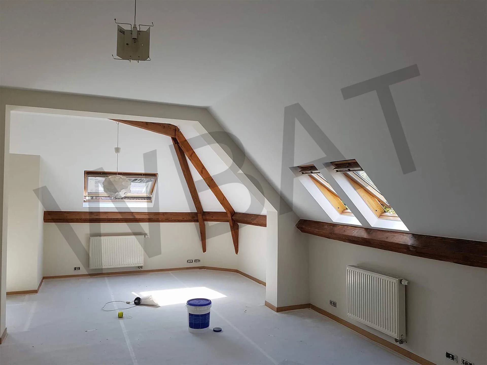 Combles après rénovation : murs blancs, poutres apparentes, fenêtres de toit et radiateur